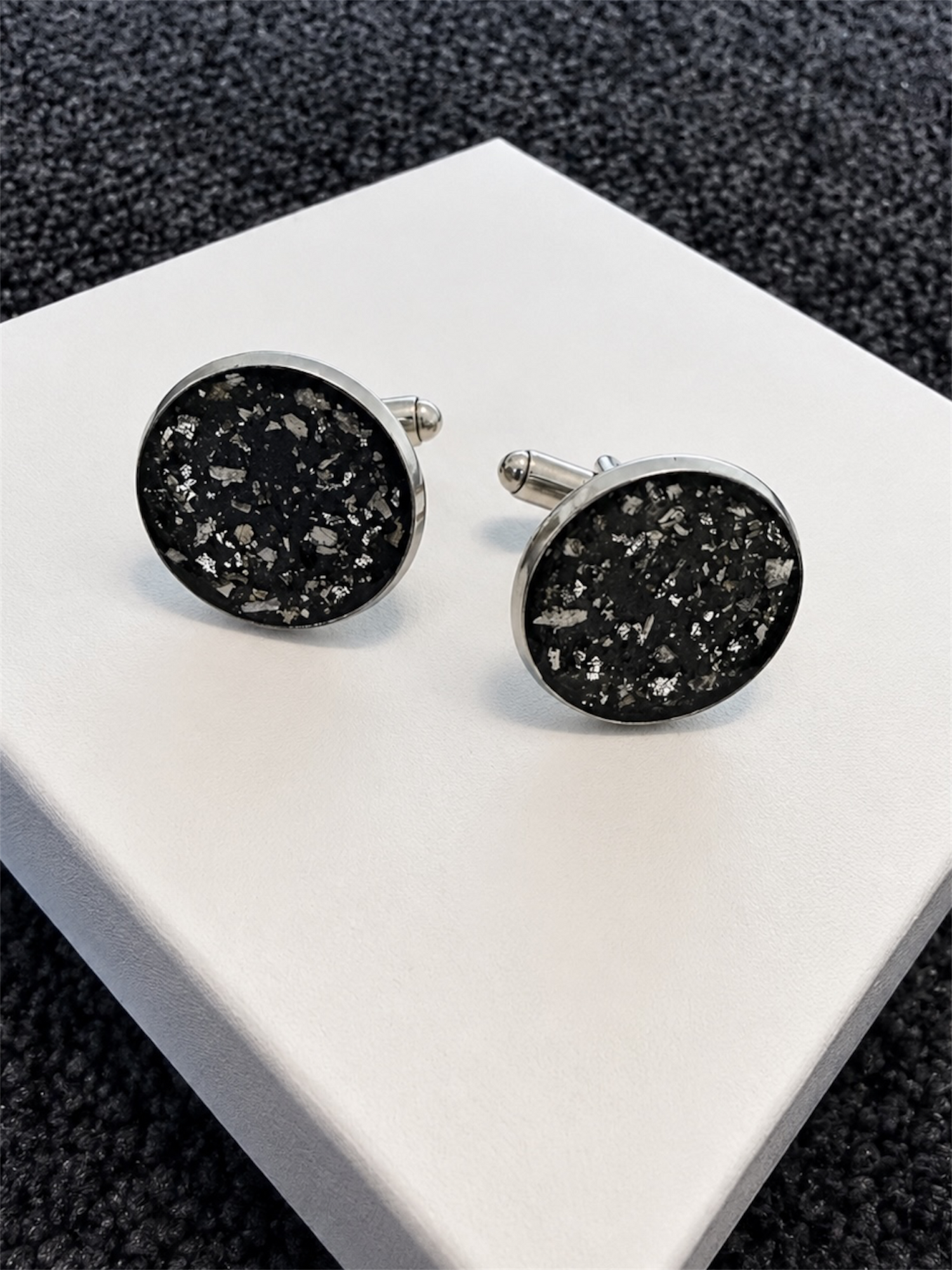 A pair of round silver cufflinks with cremation ashes speckled lovingly encased. 