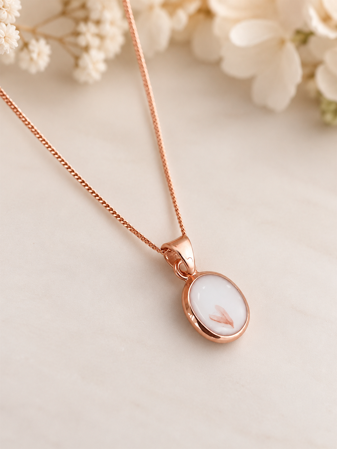 Rose gold breastmilk keepsake necklace containing preserved breastmilk and wedding flowers