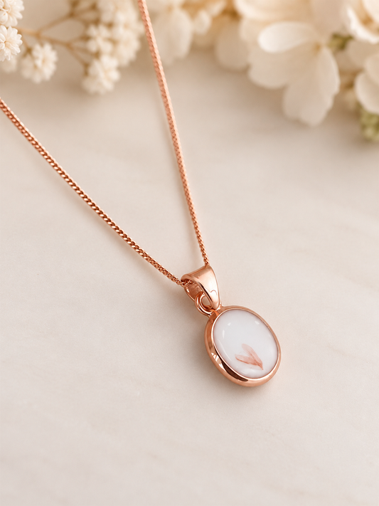 Rose gold breastmilk keepsake necklace containing preserved breastmilk and wedding flowers