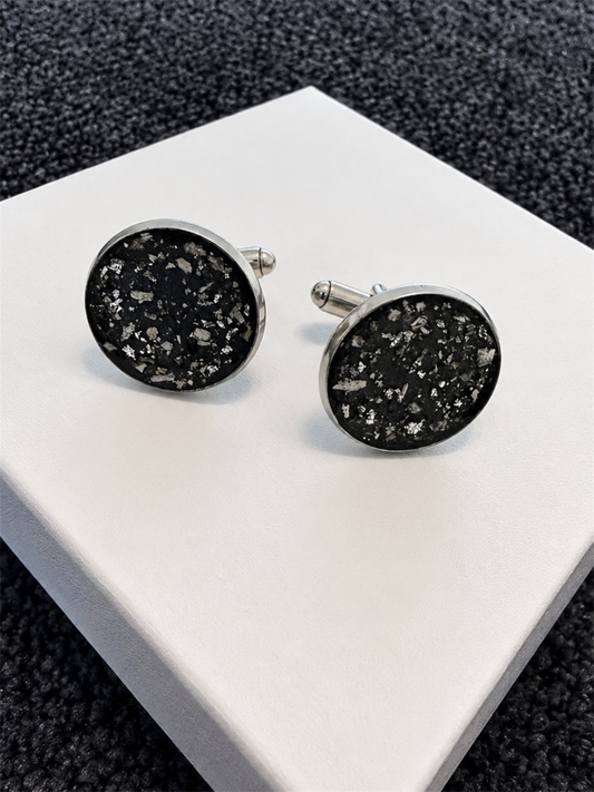 A pair of round silver cufflinks with cremation ashes speckled lovingly encased. 