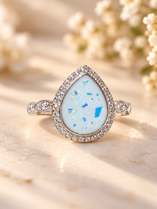 Pear-shaped breastmilk keepsake ring with blue foil details, a sparkling crystal halo and decorative sterling silver band